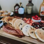 Whitness Nutrition Blogger Whitney Stuart shares a photo of a brunch board with pancakes, bacon, and fruits